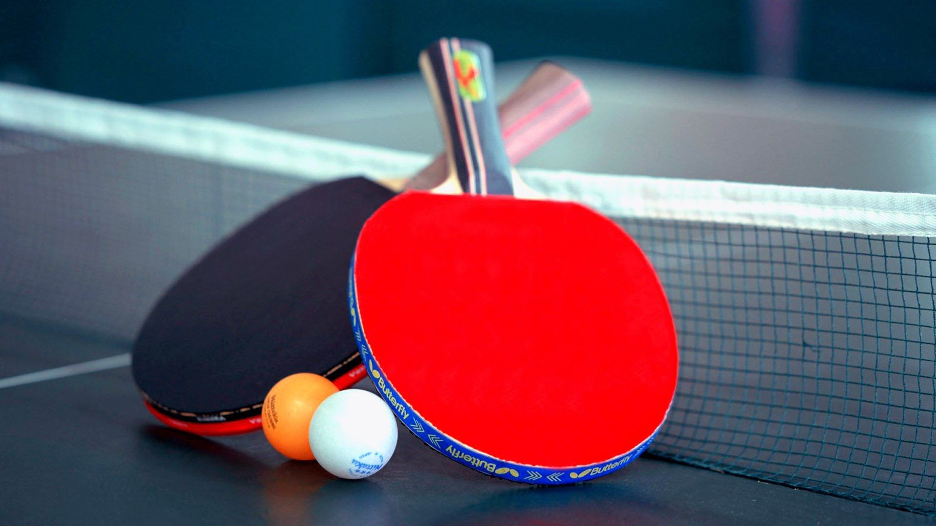 Des raquettes et une balle sur une table de ping pong.